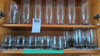 Lower shelf shows short round tumblers all made of clear glass with thick bases.