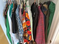 Photo of hanging ladies clothes in assorted jackets, coats, shirts with various colors and patterns.
