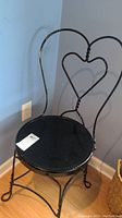Full chair showing heart-shaped metal back and round wooden seat.