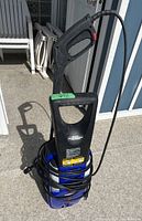 Full front view of blue Simoniz 1800 pressure washer with black handle and coiled power cord on concrete floor outdoors.
