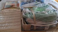 Quilts and storage bags displayed on a bed, showing a beige hanging organizer and vacuum-sealed storage bags with folded quilts inside.