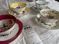 Overview of four Paragon tea cups and saucers on white cloth with handwritten lot note.