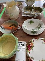 Full collection of porcelain and ceramic dishes and vase on wooden table.