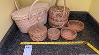 Overall view of six wicker baskets and containers on a countertop with measuring tape.