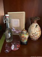 Full view of all five items including Greek pitcher, cloisonné urn, glass fish, glass bottle, and angel box