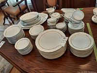 Full view of Empress China dishes arranged on a wooden table including plates, bowls, cups with saucers, cream and sugar set, gravy boat, and serving plates.