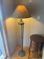 Full view of floor lamp illuminated showing textured fabric shade and metal base.
