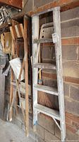 16ft wood extension ladder leaning against a wall, showing weathering and gray paint