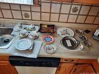 Overview of the countertop displaying various plates, teacups with saucers, a sugar bowl, and trays.