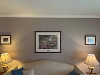 Three framed prints hanging on a beige wall above a couch with lamps on both sides, showing their size and placement.