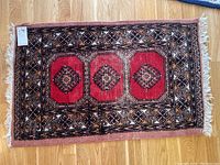 Full view of hand pulled rug on wooden floor showing overall condition, color, and pattern.