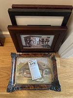 Four framed pictures leaning against the wall, varying frame styles and designs