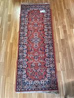 Full view of the reddish-orange runner rug displaying the overall pattern and condition.