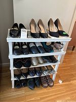 Full view of white plastic shoe rack filled with various women's shoes including heels, loafers, and sandals.