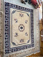 Full view of wool area rug showing center and border patterns, fringe, and wear on surface