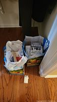 Photo shows two bags filled with paperback and hardback books. One visible book by Larry McMurtry.