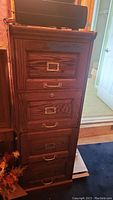 Front angled view showing all four drawers, brass-tone bail handles, and recessed label holders.