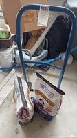 Photo of the front of the blue metal hand truck with two bags of Kingsford charcoal on its base.