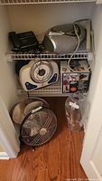 Photo showing GermGuardian humidifier, Shark Ultra vacuum, glass vase, phone system, CD player, and 18-inch fan with front unattached on shelf and floor.