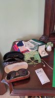 Photo showing Joan Rivers and Talbots sunglasses with cases, Ireland and other scarves on a wooden surface, including pendant and bookmark.