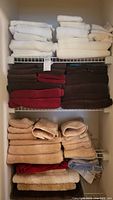 Full view of linens on shelves including white, brown, red, beige towels and bath mats