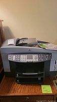 Front view of HP OfficeJet 7410 printer showing control panel, document feeder, and manual on top.