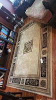 Full view of the rectangular throw rug on hardwood floor beside furnishing and bookshelves.