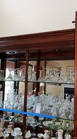 Glass cabinet with multiple Waterford crystal stemware on two shelves, including champagne glasses and other types
