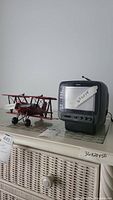 RCA portable color TV and red metal airplane model on a shelf