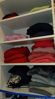 Shelves with folded sweaters of various colors including red, pink, black, lavender, and lime green.