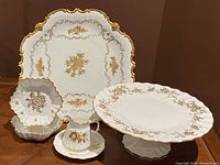 Full set of six pieces including large pedestal cake plate, creamer with under-plate, and candy dishes displayed on wood surface.
