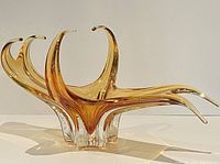 Side angle showing stretched arch design in amber glass with clear base in good light.