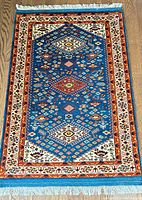 Full view of blue field with medallion pattern and fringed ends
