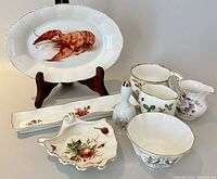 Group of various bone china items including large lobster dish, creamers, small bowls, shell-shaped dish, and toothpick holder.