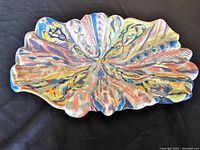 Top view of the scalloped curved-edge ceramic dish showing abstract multicolor pattern.