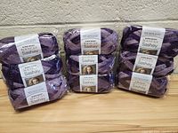 Photo showing 3 packs with 4 skeins of Red Heart Boutique Knit Cute Sashay yarn each, purple variegated color.