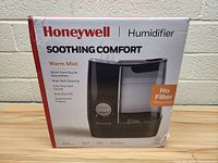 Front view of the Honeywell humidifier box showing product image and key features such as warm mist, no filter required, and comfort benefits.