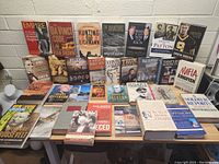Full view of a large assorted book lot on a table featuring titles on history, biography, politics, and fiction.