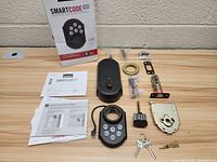 Image showing unboxed Kwikset SmartCode 909 lock components arranged on wood surface along with original box and manual.
