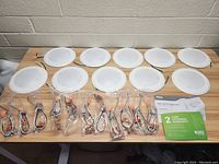 Lot of ten white disk LED downlights laid out on a wooden surface with wiring connectors in plastic bags and warranty/instruction documentation visible.