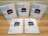 Front view of five sealed packs of Geographics blank tri-fold brochures, showing blue and orange label on packaging with product details.