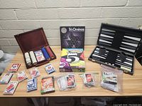 Lot of various card games, poker chips, Tri-Ominos, and backgammon set arranged on table