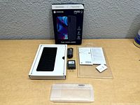 Full view of the unboxed Motorola Moto G Pure smartphone with accessories and original box on a wooden surface.