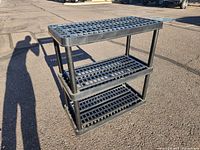 Black plastic storage shelf taken outside on paved surface in sunlight showing full unit from an angle.