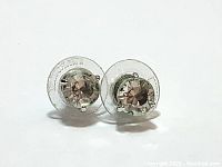 Pair of Swarovski stud earrings with clear crystals and rhodium plating shown from front with visible crystals and backing discs.