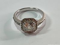 Close-up of the Swarovski ring showing the square central crystal with halo and pave band.