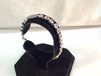 Side angle view of the Swarovski bezel set tennis bracelet on a black velvet display stand showing the clasp and crystal settings.