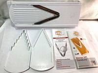 Full kit showing slicer base, three white inserts with blades, and instruction leaflets.