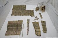 Overview of multiple sets of metal piano tuning components and tools laid out on a white surface showing variety and quantity