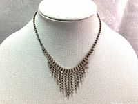 Full view of the vintage necklace displayed on a bust, showing the overall shape and fringe design.